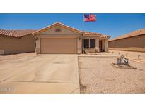 Charming single-story home with a two-car garage and well-kept desert landscaping, flying an American flag at 2202 S Lawther Dr, Apache Junction, AZ 85120