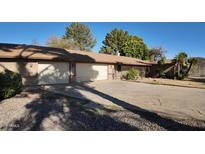 Tan single-story home featuring a two-car garage, a front yard with desert landscaping, and a concrete driveway at 3323 N 103Rd Ave, Avondale, AZ 85392