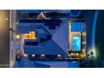 Aerial view of a home with a pool and an outdoor kitchen area illuminated by landscape lighting at dusk at 17018 W Saguaro Park Ln, Surprise, AZ 85387