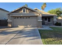 Charming single-Gathering home featuring a two-car garage and well-maintained front yard in a desert landscape at 7027 W Midway Ave, Glendale, AZ 85303