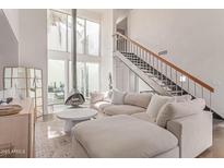Bright living room featuring modern fireplace, staircase to loft, large windows, and comfortable neutral furniture at 930 S Dobson Rd # 3, Mesa, AZ 85202