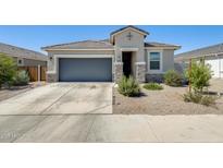 Charming single-story home featuring a gray garage door, stone accents, and well-maintained desert landscaping at 35816 W San Ildefanso Ave, Maricopa, AZ 85138