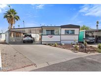 Charming mobile home with covered parking, landscaped yard, and a patriotic decorative banner at 701 S Dobson Rd # 438, Mesa, AZ 85202