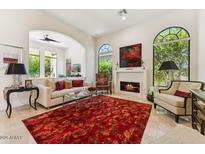 Bright living room with a fireplace, neutral furniture, arched windows, and red rug offers a cozy space at 8216 E Angel Spirit Dr, Scottsdale, AZ 85255