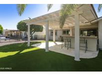 Inviting backyard features a covered patio, outdoor bar, and lush artificial grass at 922 S Ember Cir, Mesa, AZ 85208