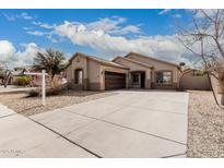Charming single-story home showcasing a neutral color palette, a spacious driveway, and a two-car garage at 9325 W Elwood St, Tolleson, AZ 85353