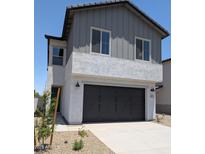 Two-story home featuring a black two-car garage and low-maintenance desert landscaping at 9408 E Sequence Ave, Mesa, AZ 85212