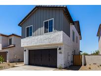 Charming two-story home featuring grey siding, a stucco base, dark garage door, and well-manicured landscaping at 9408 E Sequence Ave, Mesa, AZ 85212