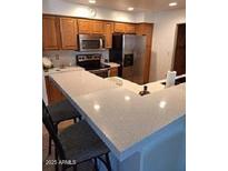 Bright kitchen features wooden cabinets, stainless steel appliances and a large quartz breakfast bar at 4202 E Broadway Rd # 223, Mesa, AZ 85206