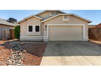 Beige single-story home featuring a two car garage and desert landscaping in front at 8668 N 107Th Dr, Peoria, AZ 85345