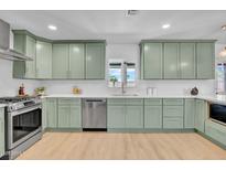 Modern kitchen featuring light green cabinets, stainless steel appliances, and light hardwood floors at 2712 N 20Th Dr, Phoenix, AZ 85009