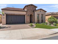 Charming home featuring a brick accents, a two-car garage and manicured artificial lawn at 129 E Los Andes Ln, Queen Creek, AZ 85140