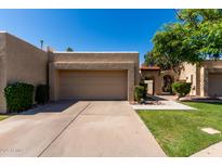 Beige home showcasing an attached two-car garage, desert landscaping and an arched doorway at 2059 E Brown Rd # 35, Mesa, AZ 85213