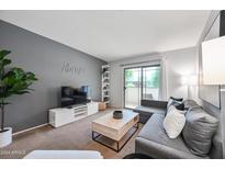 Comfortable living room features gray walls, modern furniture, and sliding glass door to patio at 357 E Thomas Rd # A208, Phoenix, AZ 85012