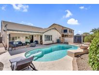 Inviting pool area with blue pool, patio seating, and well-maintained landscaping, perfect for outdoor relaxation at 38771 N Dena Dr, San Tan Valley, AZ 85140