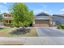 Inviting single-Gathering home with a well-maintained front yard and a charming, tree-lined paver driveway at 3058 E Spring Wheat Ln, Gilbert, AZ 85296