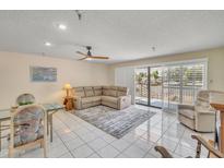 Bright living room with neutral tones, tiled floors, ceiling fan, and a door to the outside balcony at 453 S Parkcrest -- # 416, Mesa, AZ 85206