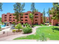 Beautiful condo complex exterior featuring lush landscaping and a community pool with a waterfall feature at 12222 N Paradise Village S Pkwy # 220, Phoenix, AZ 85032