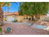 Charming single-story home featuring desert landscaping, a tiled roof, and a spacious two car garage at 15014 N 48Th Pl, Scottsdale, AZ 85254