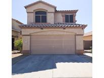 Beige two-story home featuring a two-car garage and a well-maintained concrete driveway at 1902 N 106Th Ave, Avondale, AZ 85392