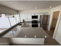 Beautiful kitchen with new stainless steel appliances and breakfast bar featuring grey countertops at 4849 W Northern Ave, Glendale, AZ 85301