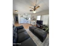 Cozy living room and kitchen area with laminate floors, ceiling fan, and comfortable leather seating at 7807 E Main St # H-20, Mesa, AZ 85207