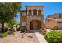 Charming two-story home with a stone facade, arched entryway, balcony, and desert landscaping at 11959 W Pierce St, Avondale, AZ 85323