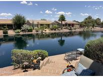 Waterfront backyard with a brick patio, lake view and outdoor seating perfect for relaxing at 20119 N Laguna Way, Maricopa, AZ 85138