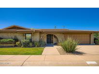 Charming brick home featuring a manicured lawn, arched entryway, and attached garage at 8355 E Vía De Los Libros --, Scottsdale, AZ 85258