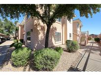 Exterior view of condo building with well-maintained landscaping, stairs, and tan stucco at 10030 W Indian School Rd # 101, Phoenix, AZ 85037