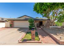 Charming single-story home with well-manicured lawn, brick accents, mature trees, and a two-car garage at 4627 W Laurie Ln, Glendale, AZ 85302