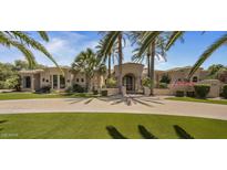 An elegant stucco home with a circular driveway, palm trees, and manicured landscaping provides a grand entrance at 6305 E Arabian Way, Paradise Valley, AZ 85253
