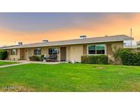 Charming single-story home with well-maintained landscaping and cozy curb appeal under a beautiful sunset at 11122 W Desert Butte Dr, Sun City, AZ 85351