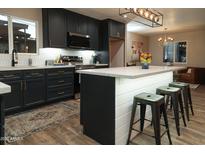 Modern kitchen features dark cabinetry, stainless appliances, white countertops, and stylish island with bar stool seating at 236 E Minton Dr, Tempe, AZ 85282