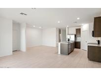 Bright open-concept living area next to a modern kitchen featuring stainless steel appliances and an island at 25464 W Fraktur Rd, Buckeye, AZ 85326