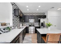 Modern kitchen boasts stainless steel appliances, black cabinetry, patterned backsplash, and white countertops at 240 W Juniper Ave # 1020, Gilbert, AZ 85233