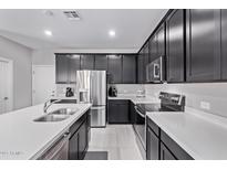 Modern kitchen featuring dark cabinets, stainless steel appliances, and a large island with quartz countertops at 2625 S Peppertree Dr # 101, Gilbert, AZ 85295