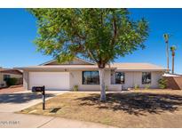 Charming single-story home featuring an attached two-car garage and mature tree in the front yard at 3307 W Mescal St, Phoenix, AZ 85029