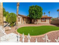 A single-story home with a charming front yard, lush lawn, and mature trees at 5649 W Holly St, Phoenix, AZ 85035