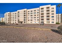 Low-angle exterior view of the apartment building showing balconies, desert landscaping, and a clear blue sky at 7920 E Camelback Rd # 609, Scottsdale, AZ 85251