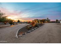 Expansive desert landscaping and warm exterior lighting highlight this beautiful home at sunset at 38106 N 2Nd Ln, Phoenix, AZ 85086