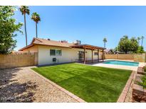 Inviting backyard featuring artificial grass, a refreshing pool, and a covered patio area at 3913 N 86Th St, Scottsdale, AZ 85251