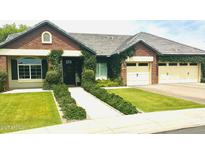 Charming brick home with a well-manicured lawn, lush greenery, and a three-car garage at 4824 S Brice --, Mesa, AZ 85212