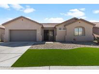 Inviting single-story home featuring a well-manicured artificial lawn and desert landscaping, providing great curb appeal at 4933 W Melody Ln, Laveen, AZ 85339