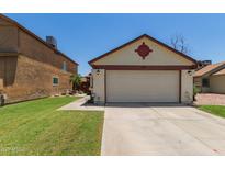 Inviting home featuring a two-car garage, well-kept lawn, and desert landscaping elements at 6319 W Mercer Ln, Glendale, AZ 85304