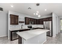 Modern kitchen with stainless steel appliances, dark wood cabinetry, and a large island at 7423 S 28Th Pl, Phoenix, AZ 85042