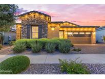 Charming stone accented home featuring an attached garage, manicured shrubs, and festive outdoor lighting at 10650 E Palladium Dr, Mesa, AZ 85212