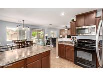 Open kitchen boasts stainless steel appliances, tiled floor, dark cabinets and an adjacent dining area at 40316 W Hopper Dr, Maricopa, AZ 85138