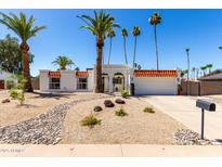Charming white home with desert landscaping, red tiled roof and numerous palm trees at 5211 E Winchcomb Dr, Scottsdale, AZ 85254