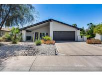 Charming single-story home showcasing desert landscaping, neutral tones, and a black-trimmed roof against a clear blue sky at 8625 E San Alfredo Dr, Scottsdale, AZ 85258